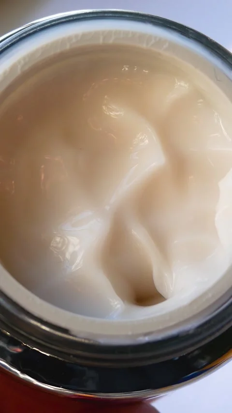 A womans hand opens a jar of cream, tries a white face cream with her finger. Stock Footage 314043673