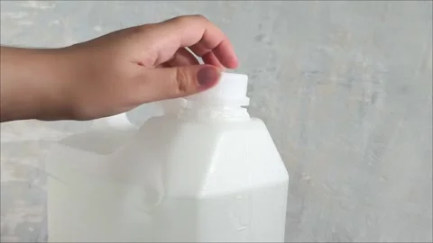A womans hand opens the lid of a white plastic canister on the background of a Stock Footage 313834538
