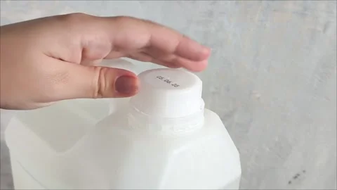 A womans hand opens the lid of a white plastic canister on the background of a Stock Footage 313834543