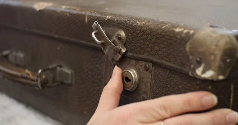 A woman's hand opens the lock on an old leather suitcase. A retro suitcase Stock Footage 231566990