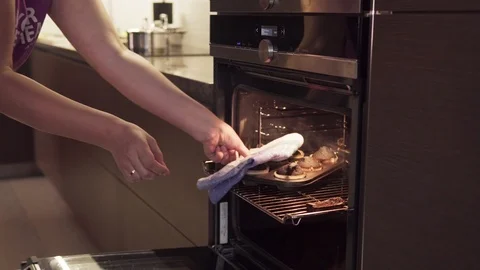 Woman's hand opens oven, takes burnt cookies, smoke from overcooked food coming Stock Footage 89947022