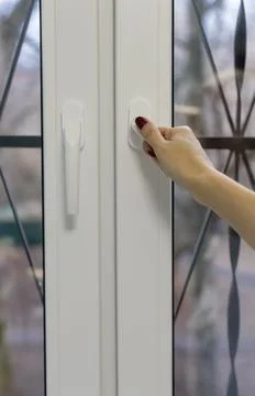 A woman's hand opens a plastic window by the handle Stock Photos