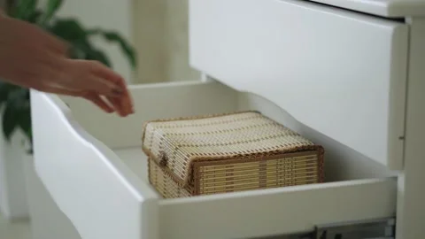A woman's hand opens a shelf with a drawer and takes it out in a room at home Stock Footage 153555176