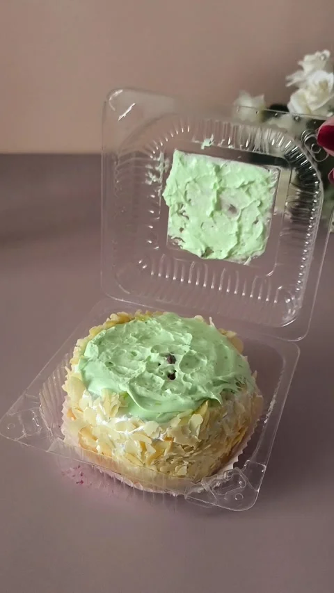 A womans hand opens a transparent plastic container with a pie with cream and Stock Footage 324697983