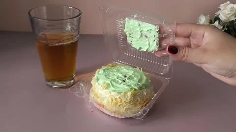 A womans hand opens a transparent plastic container with a pie with cream and Stock Footage 324698060