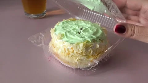 A womans hand opens a transparent plastic container with a pie with cream and Stock Footage 324698204