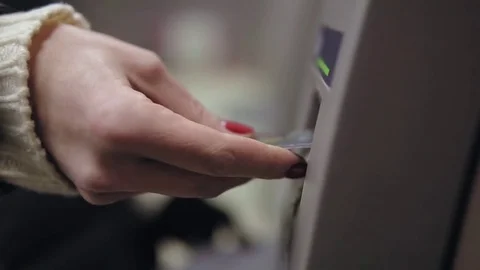 Woman's hand with painted red nails inserting credit card to ATM, using it and Видео 72299159