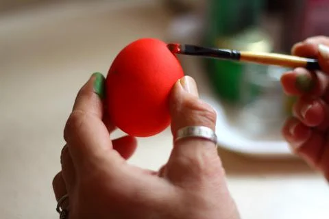 A woman's hand paints an Easter egg. Stock Photos
