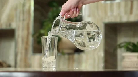 A woman's hand picks up a jug and pours water into a glass Stock Footage 337192095