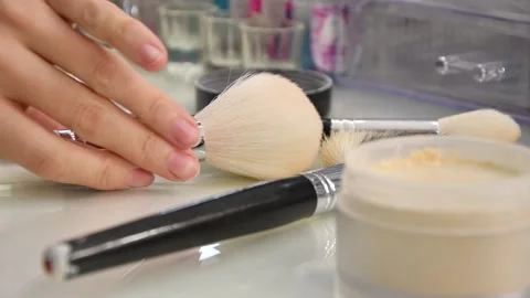A woman's hand picks up a large makeup brush from the table in a beauty salon. Video stock 143505865