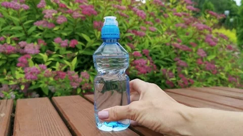 A woman's hand places a plastic bottle with water on a wooden surface. Stock Footage 337567717