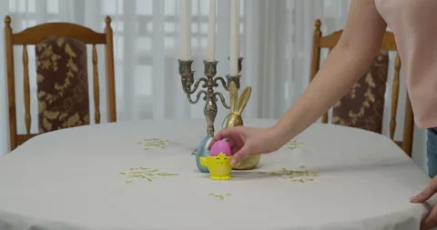 The woman's hand places on a table a support with a pink painted egg. table for Stock Footage 172257220