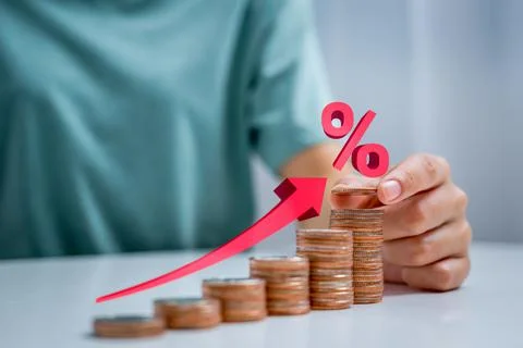 Woman's hand placing coin on stack of coins arranged in upward position and i Stock Photos