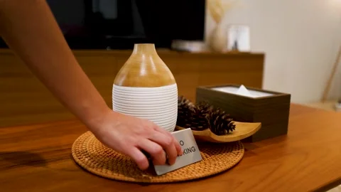 Womans hand placing silver no smoking sign on wooden table next to essentia.. Stock Footage 333320286
