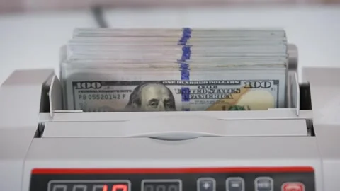 Womans hand placing stack of hundred dollar bills into automatic counting m.. Stock Footage 337541454