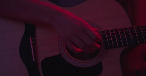 Womans hand playing on guitar , close up shot , red lights concept , drammatic m Stock Footage 117475906
