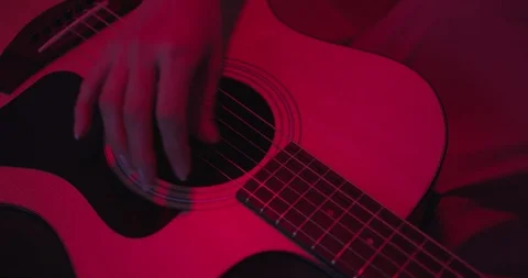 Womans hand playing on guitar , close up shot , red lights concept , drammatic m Stock Footage 117476356