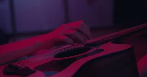 Womans hand playing on guitar , close up shot , red lights concept , drammatic m Stock Footage 117476366