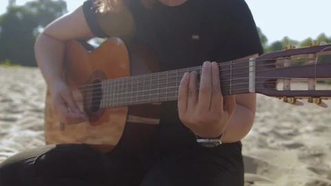 Woman's hand playing guitar on sandy beach, sunny day Stock Footage 127717218