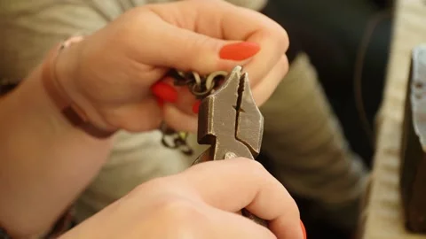 Woman's hand with pliers makes chain mail Vídeos de archivo 200486135