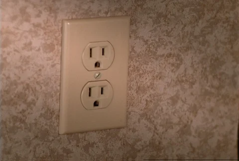 Woman's hand plugging electrical cord into wall socket Stock Footage 86918953