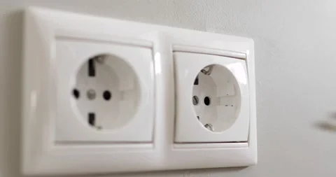 Woman's hand plugging white power plug into white multiple socket indoors. Stock Footage 156804916