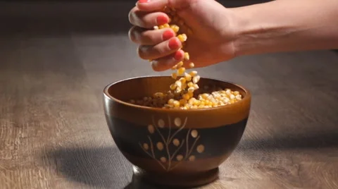 Woman's hand pouring pop corn into a bowl Stock Footage 62063206
