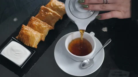 A woman's hand pours tea from a jug into a cup. Breakfast concept. Tea time Stock Footage 161367368
