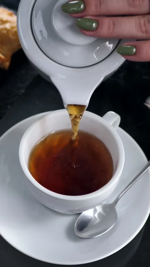 A woman's hand pours tea from a jug into a cup. Breakfast concept. Tea time Stock Footage 305209958