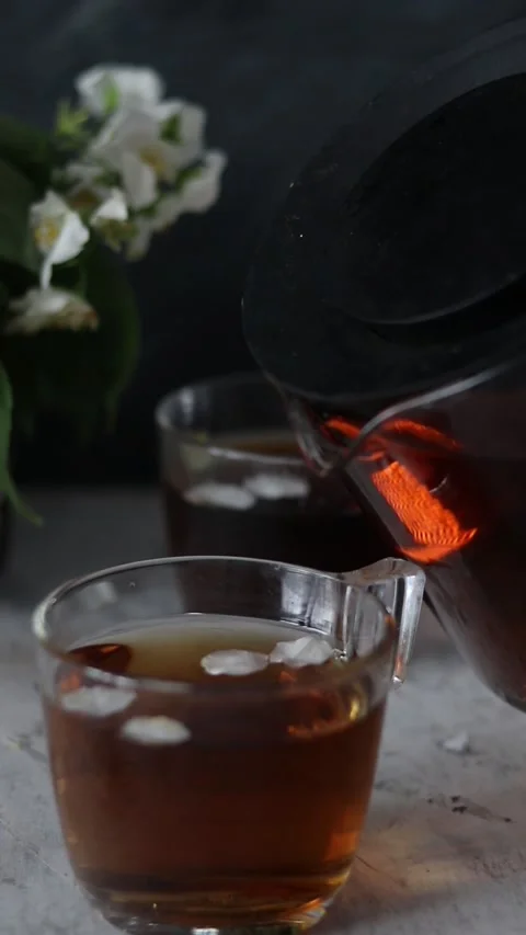 A woman's hand pours tea from a teapot. Low key Stock Footage 156207589