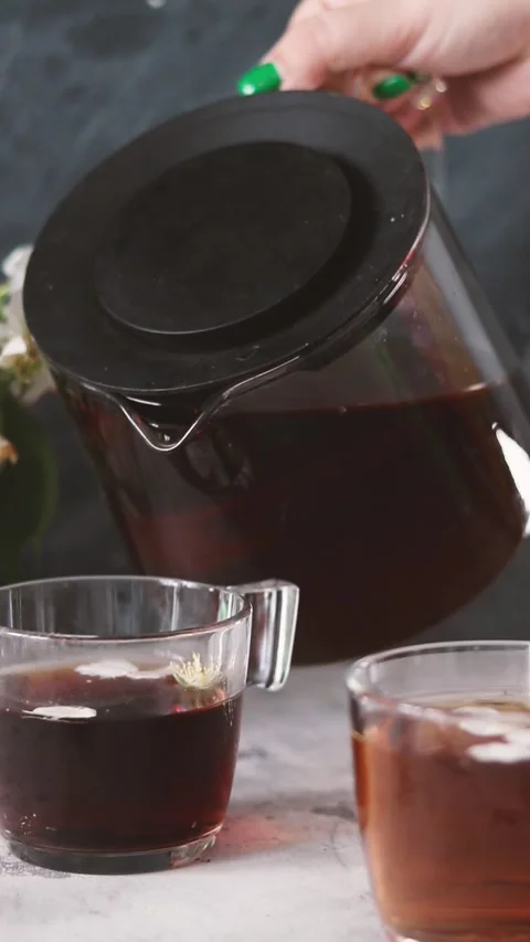 A woman's hand pours tea from a teapot. Low key Stock Footage 156207644