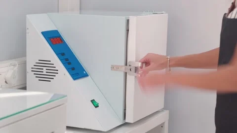 The woman's hand presses the button and opens the sterilizer door autoclave. 库存影片 144639957