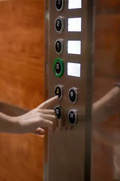 A woman's hand presses a button in the elevator to call for help. Modern elev Fotos de archivo