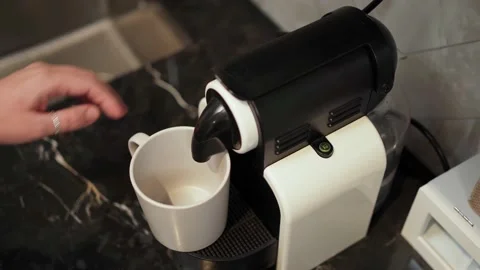 A woman's hand presses a button on a small capsule coffee machine and the coffee Stock Footage 196295207