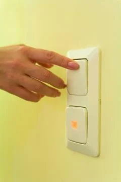 A woman's hand presses the button of the switch. Stock Photos