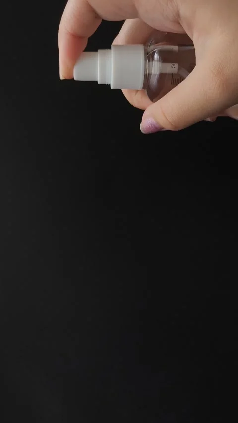 A womans hand presses the button of a transparent plastic spray bottle and Video stock 314975011