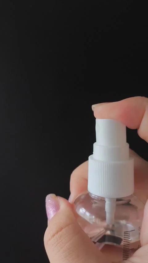 A womans hand presses the button of a transparent plastic spray bottle and Stock Footage 314975093