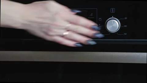 A woman's hand presses the oven control buttons, thereby turning on the heating. Stock Footage 169104936