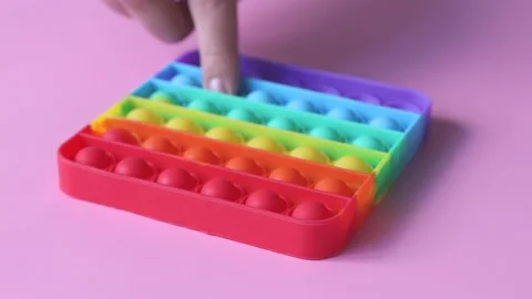 A woman's hand presses a square shape pop it silicone toy. Trending game Stock Footage 155460137