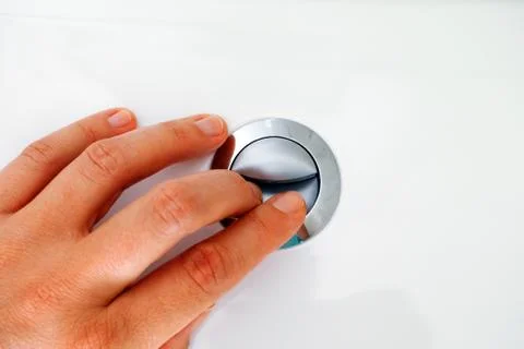 Womans hand pressing button for flushing. Stock Photos