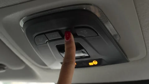 Woman's hand pressing the car interior light button Stock Footage 345012549