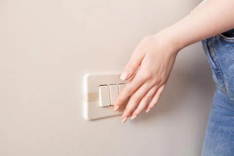Woman's hand pressing light switch at the wall. Stock Photos