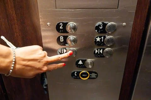 Woman's hand pressing a silver elevator button 스톡 사진