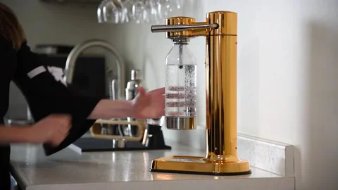 Woman's hand pulling metal lever to make fresh sparkling water using carbonator. Stock Footage 157768739