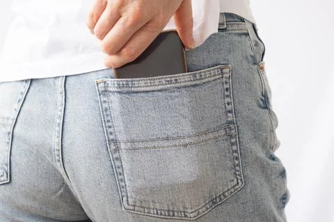 A woman's hand pulls out a mobile phone from the back pocket of her jeans. Close Stock Photos