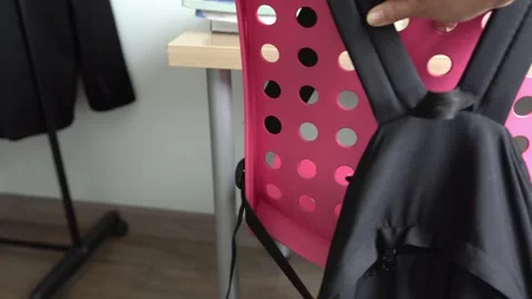 A woman's hand pulls a pink chair with a schoolboy's rucksack to the table. Stock Footage 309093220