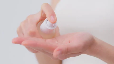A woman's hand with a pump container, serum, and lotion in her hand Vidéo 343594090
