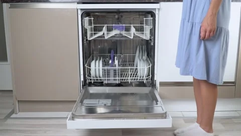A woman's hand pushes out the empty top shelf of the dishwasher with the bottom Stock Footage 202167880