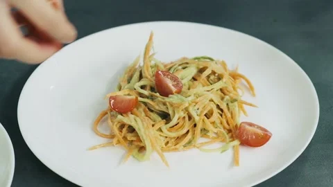 Woman's hand put cutted cherry tomatoes on the plate over the grated cucumber Video stock 136182373