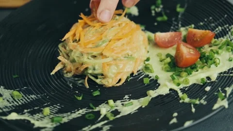 Woman's hand put a cutted cherry tomatoes on the top of dish with grated Stock-Footage 136182430